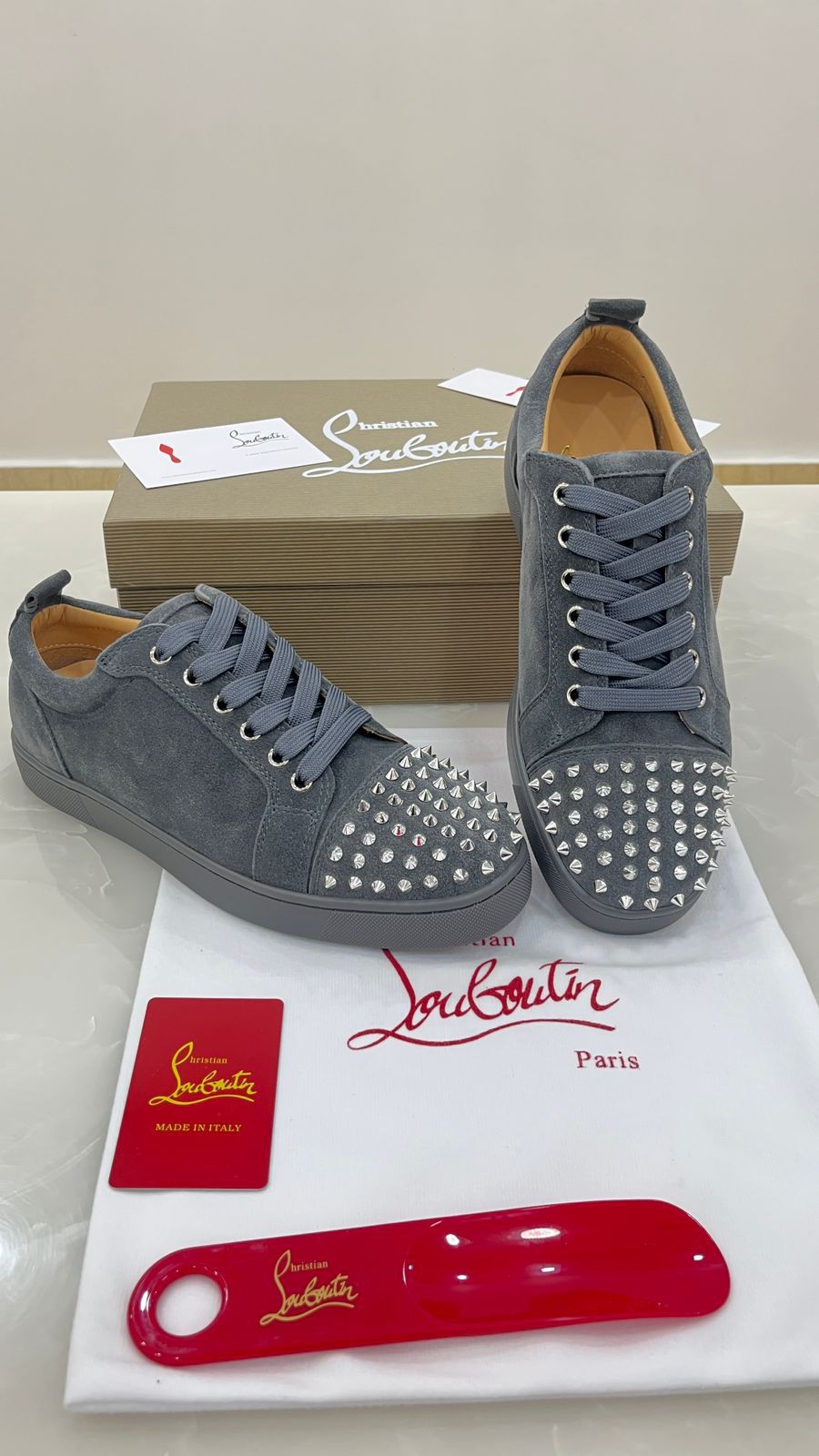 Christian Louboutin Louis Junior Spikes sneakers feature a grey suede